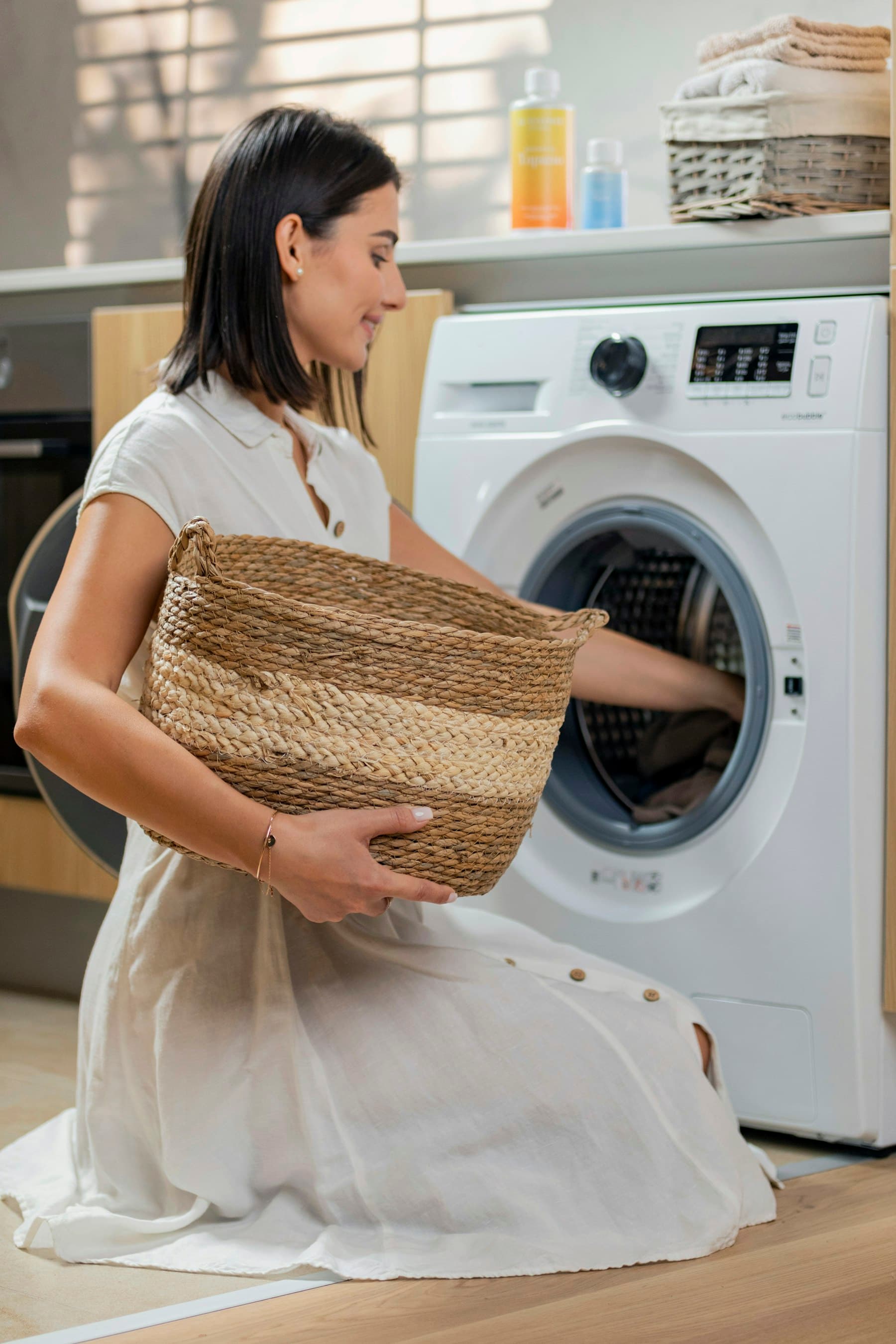 Personne chargeant un lave-linge à hublot avec un panier en osier