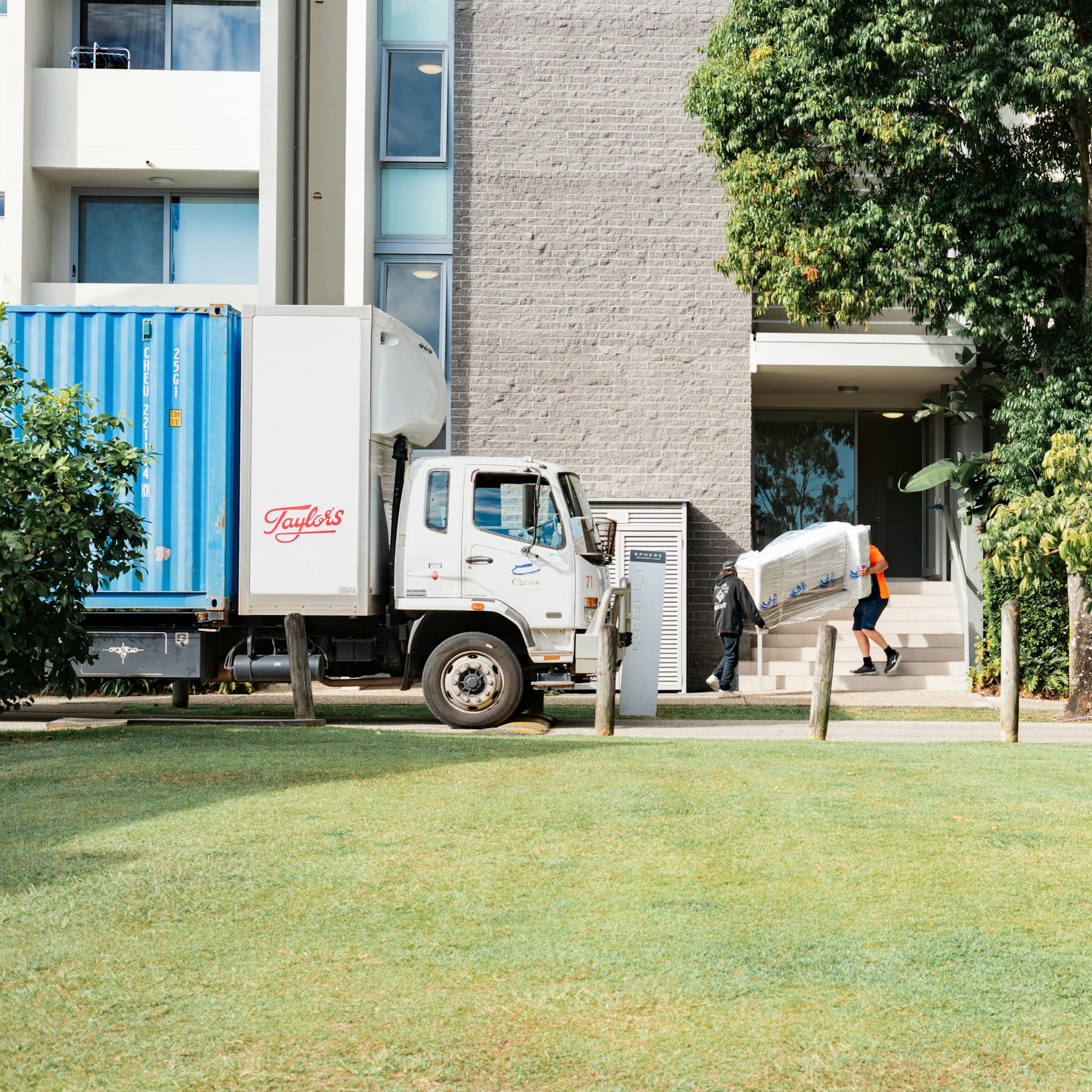 Camion de livraison garé devant un immeuble, un livreur porte un appareil emballé